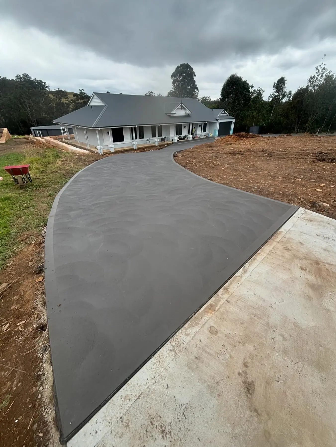Long curved driveway leading to a white weatherboard house