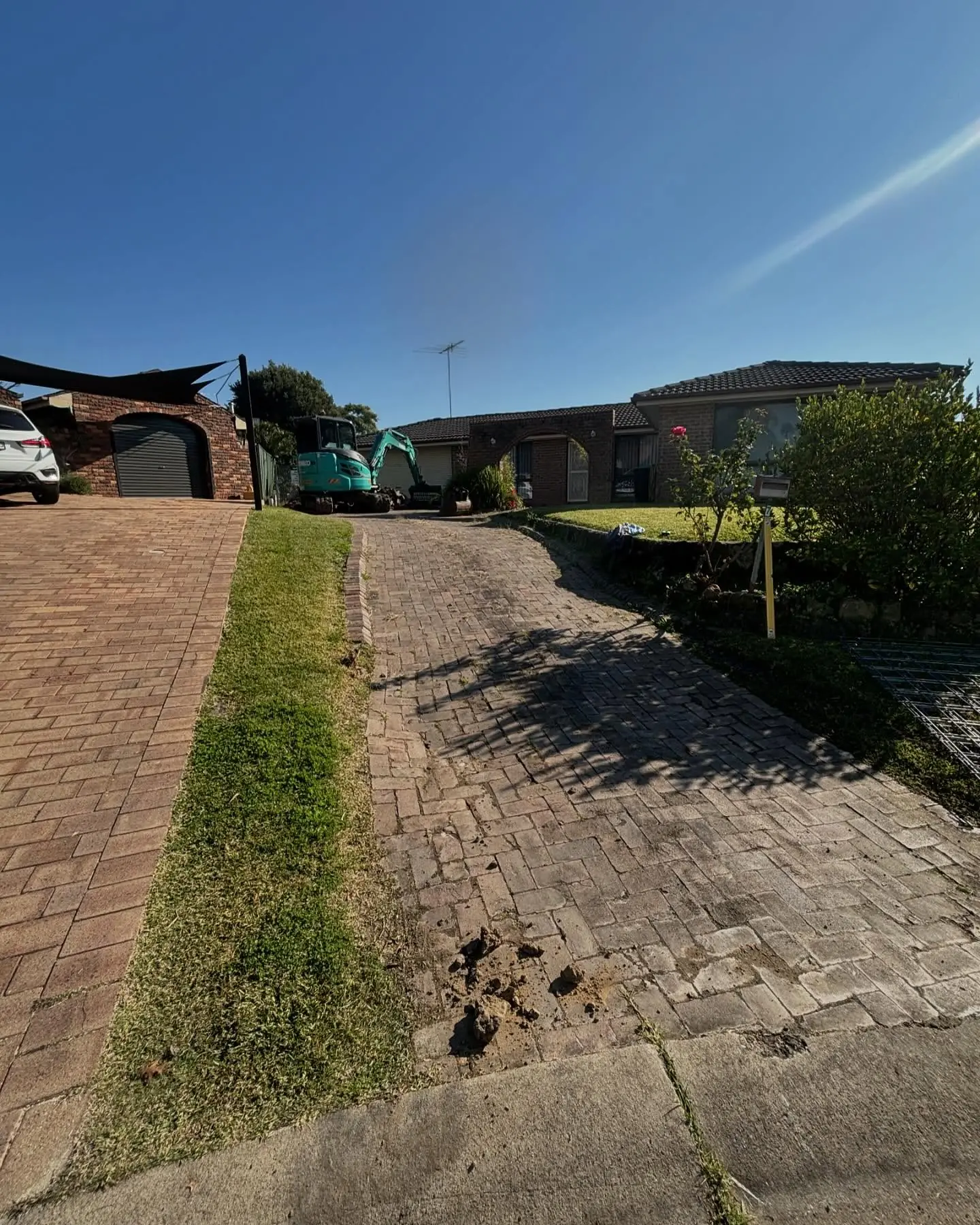 Old brick-paved driveway with a grass strip, before the job