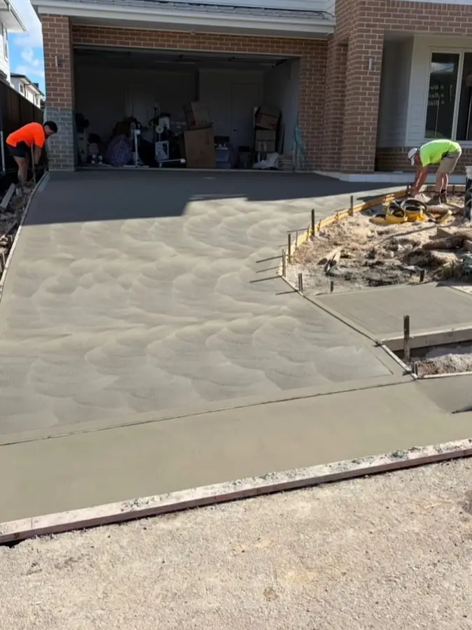 Crew pouring driveway brick house