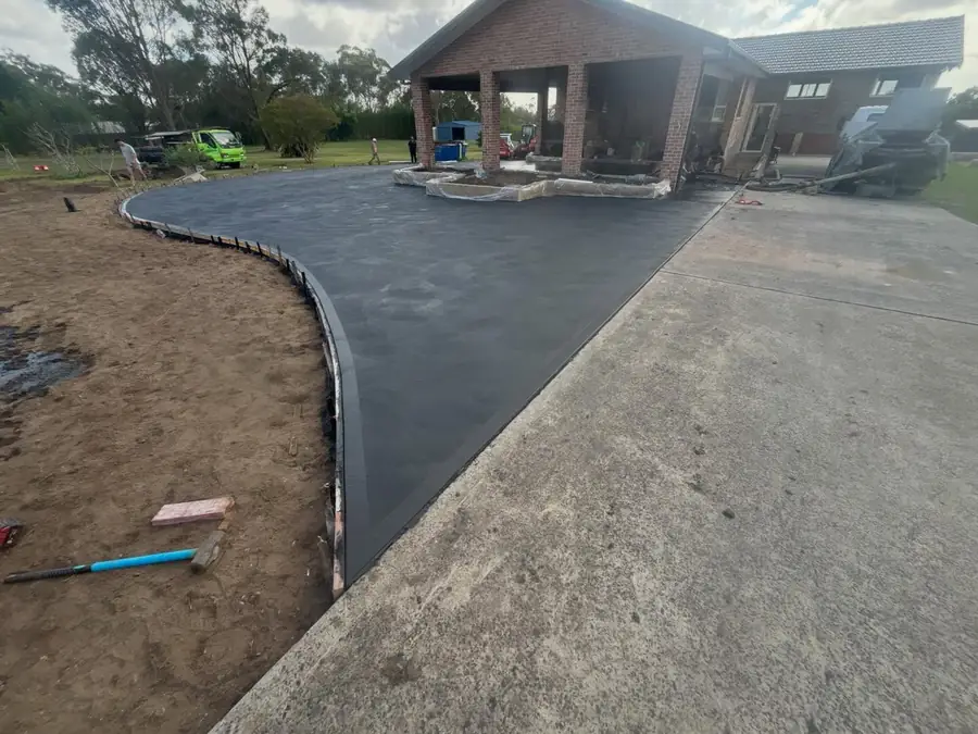Curved two-tone driveway sweeping up to a brick house on acreage